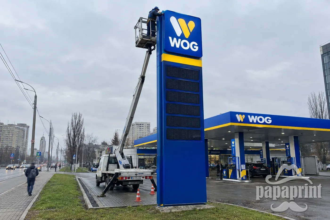 Монтаж рекламної стели WOG на АЗС у Києві: синій пілон із жовтою смугою та логотипом