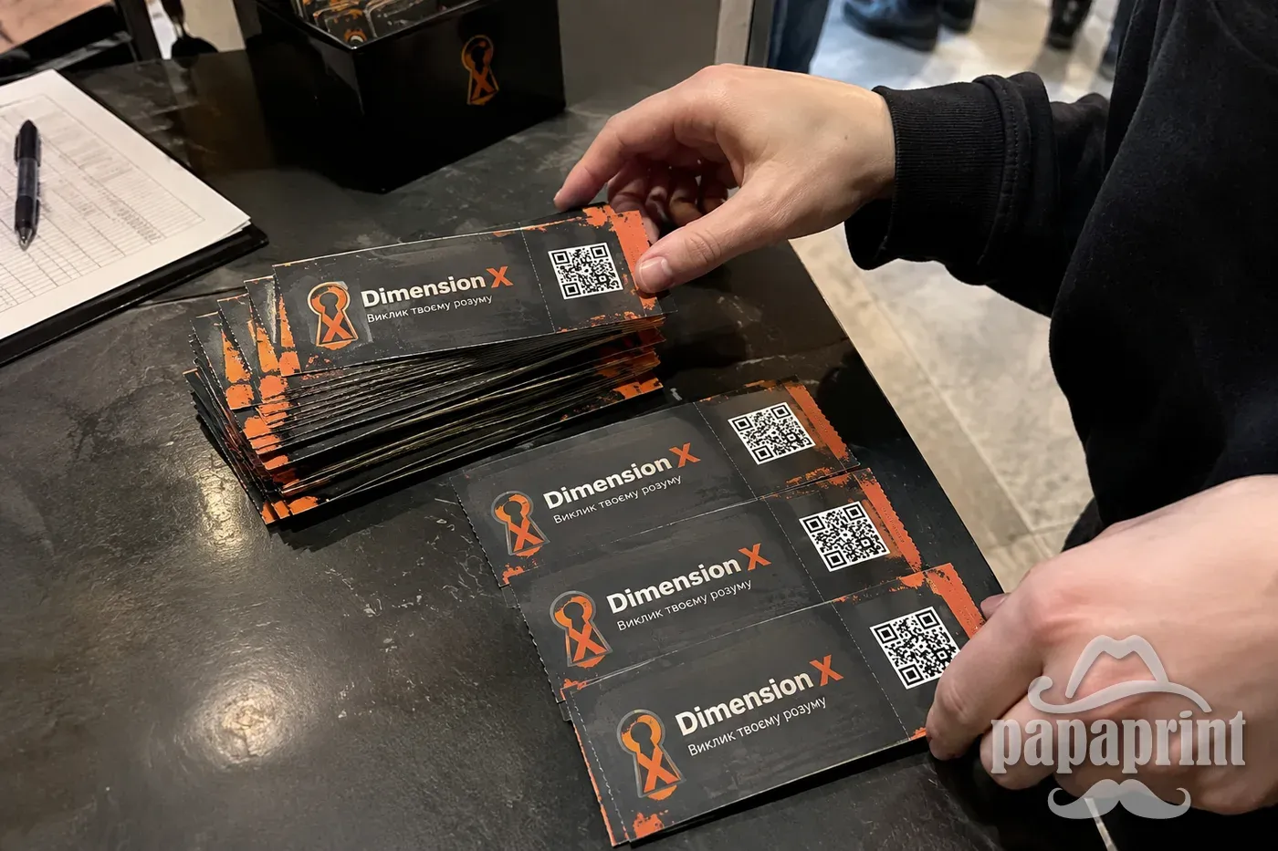 Стопка персоналізованих квитків Dimension X з унікальними QR кодами на столі, демонструючи можливості цифрового друку PapaPrint.