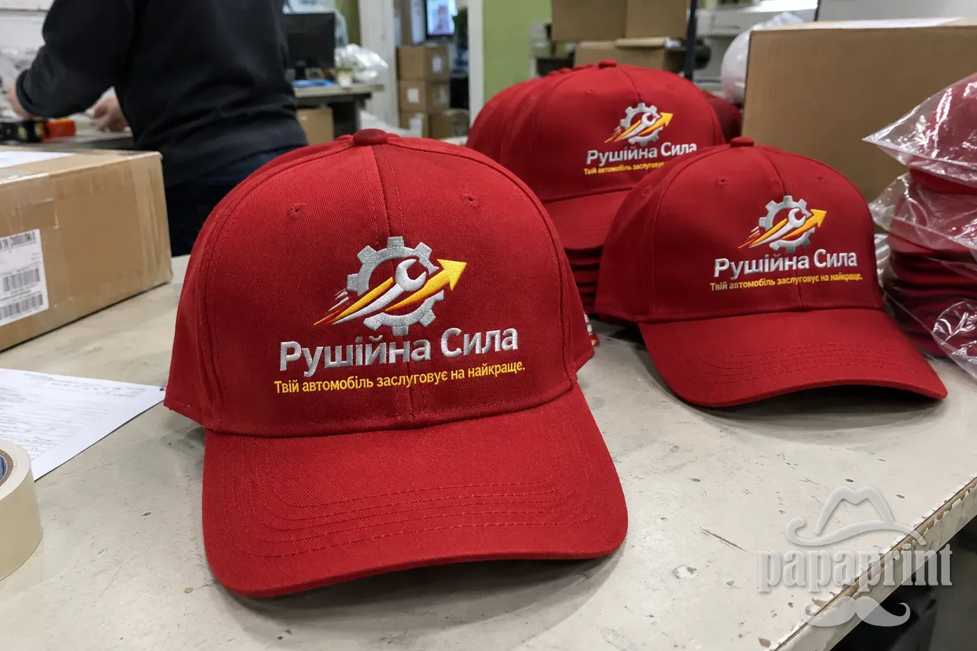 Червона бейсболка Рушійна Сила з вишивкою на столі PapaPrint перед відправкою