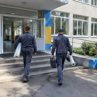 Бригада монтажників заносить плівку в школу (ілюстрація)