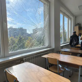 Тріснуте вікно класу втрималось на плівці, на партах немає скла (ілюстрація)