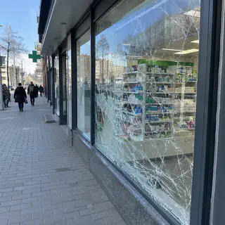 Вітрина аптеки тріснула, але втрималась у рамі на плівці, уламків на тротуарі немає (ілюстрація)