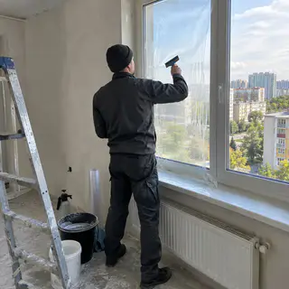 Монтажник клеит пленку на только что установленное окно (иллюстрация)