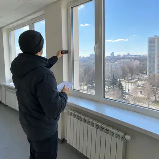 Замірник вимірює велике вікно лазерним далекоміром (ілюстрація)
