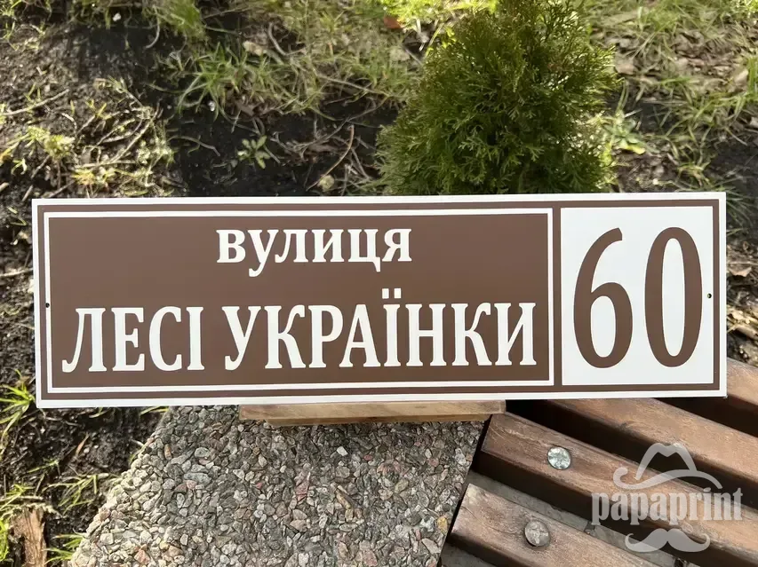 Металева адресна табличка з назвою вулиці і великим номером будинку